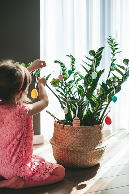 Bambina che decora una pianta con le uova di Pasqua
