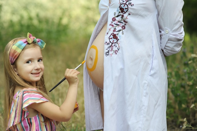 Bambina che dipinge il sole sulla pancia della mamma incinta