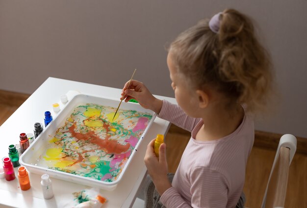 Bambina che disegna con ebru vernici sull'acqua