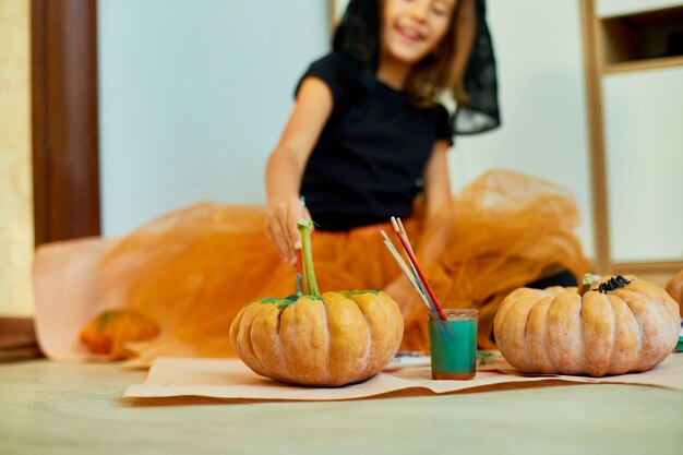 Bambina che disegna la faccia sulla zucca arancione di Halloween Jack-O-Lantern