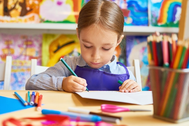 Bambina che disegna nella scuola materna