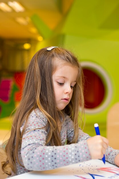 Bambina che disegna nella stanza dei giochi