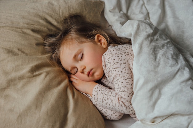 Bambina che dorme nel letto di casa, vista dall'alto