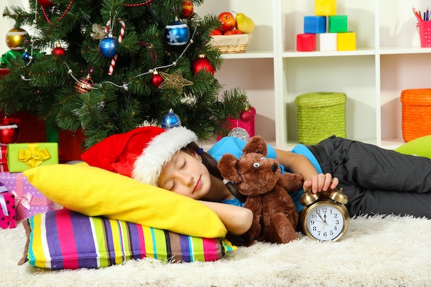 Bambina che dorme vicino all'albero di Natale