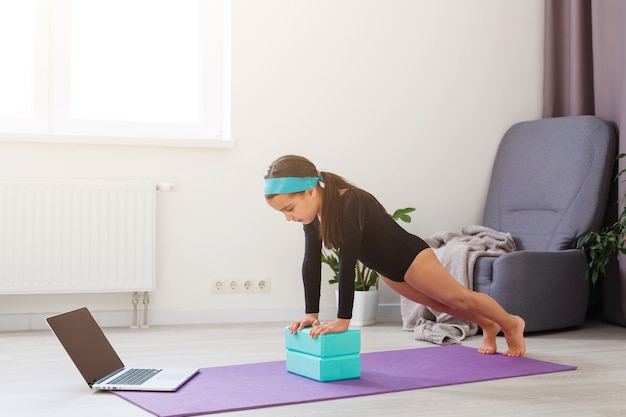 Bambina che fa esercizio di yoga in palestra con grandi finestre sullo sfondo