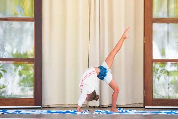 Bambina che fa esercizio di yoga sul terrazzo all'aperto