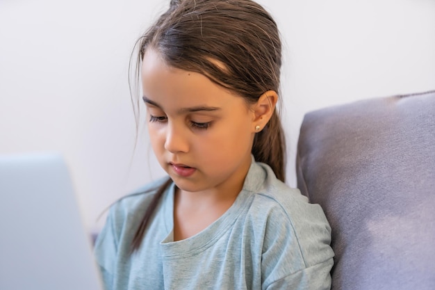 Bambina che fa i compiti a casa e che utilizza un computer portatile