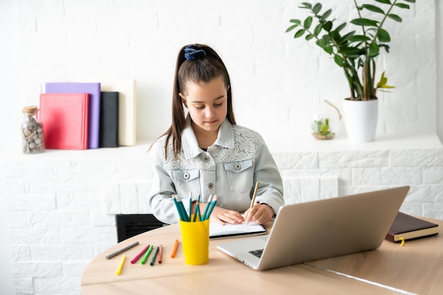 Bambina che fa i compiti a casa e usa un laptop