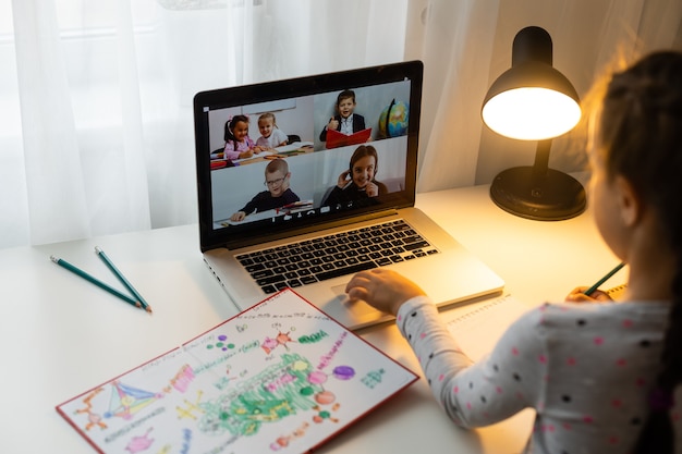 Bambina che fa i compiti a casa e usa un laptop