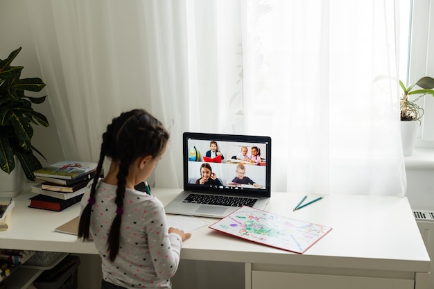 Bambina che fa i compiti a casa e usa un laptop