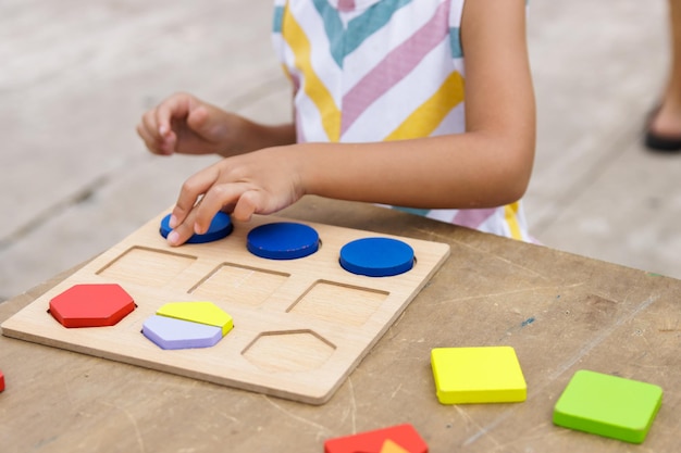 Bambina che fa puzzle di legno colorato