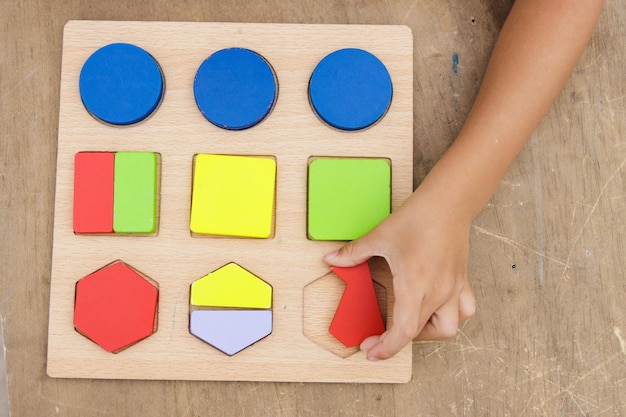 Bambina che fa puzzle di legno colorato