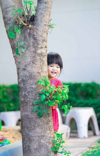 Bambina che furtivamente dietro l&#39;albero nel parco