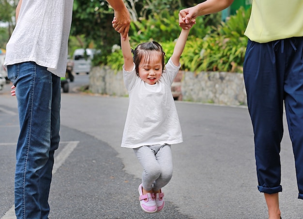 Bambina che gioca altalena con i genitori