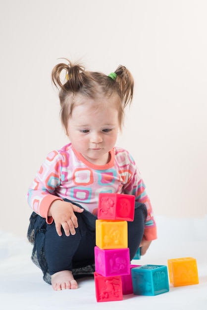Bambina che gioca con cubi colorati su sfondo bianco