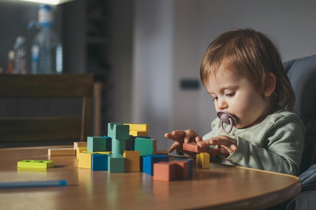 Bambina che gioca con i blocchi di legno seduti a casa a giocare a costruzioni