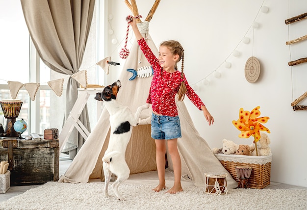 Bambina che gioca con il fox terrier liscio nella stanza dei bambini