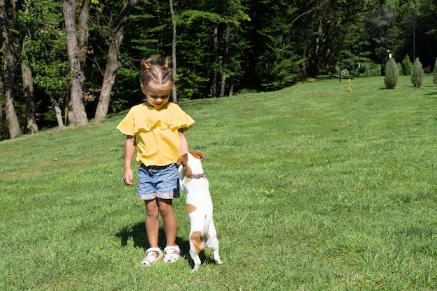 Bambina che gioca con il suo cane Jack Russell Terrier nel parco