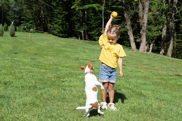 Bambina che gioca con il suo cane Jack Russell Terrier nel parco