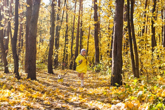 Bambina che gioca con il suo cane nella foresta autunnale