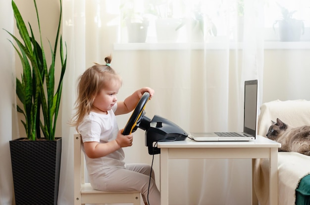 Bambina che gioca con il volante di un computer. Bambina che gioca al videogioco - corse automobilistiche. Futuro pilota. Prepararsi per la guida professionale. Bambino alla guida di un'auto.