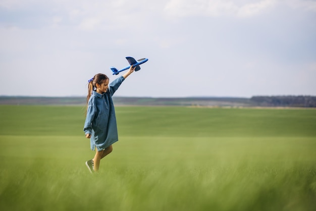 Bambina che gioca con l'aereo giocattolo nel campo