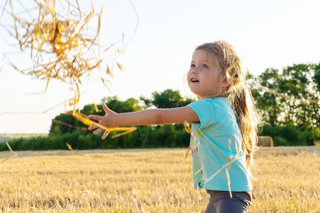 Bambina che gioca con l'erba di grano nel campo