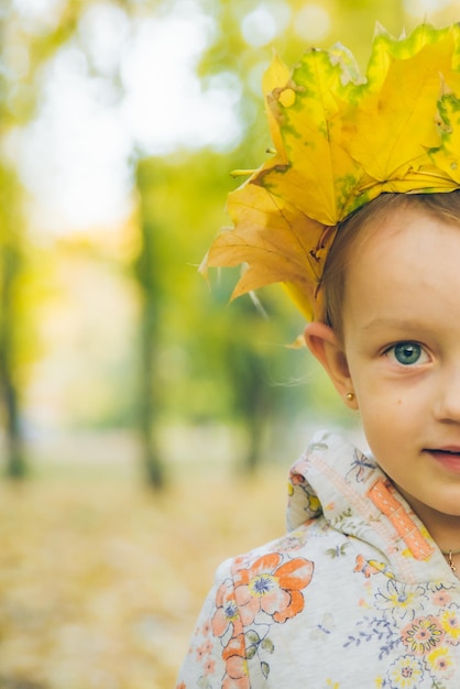 Bambina che gioca con la corona di foglie d'acero