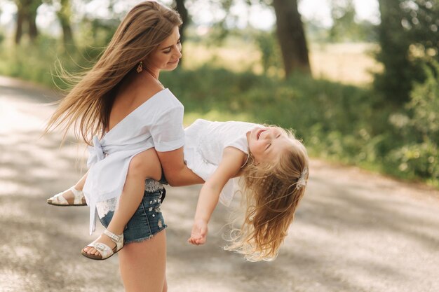 Bambina che gioca con la mamma nel parco in un giorno d'estate durante il tramonto