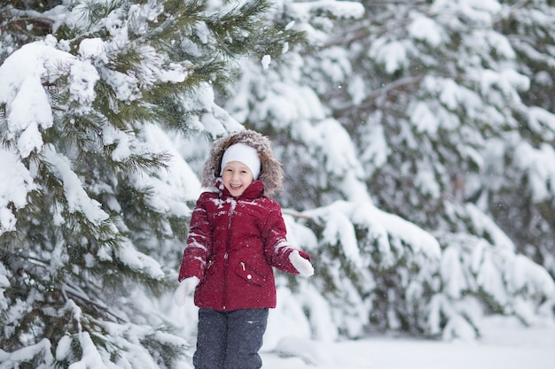 bambina che gioca con la neve nella foresta