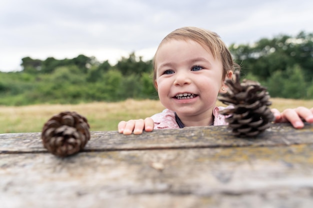 Bambina che gioca con le pigne da un albero