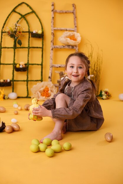 Bambina che gioca con le uova di Pasqua e la decorazione tradizionale di Pasqua del pulcino nello stile rurale