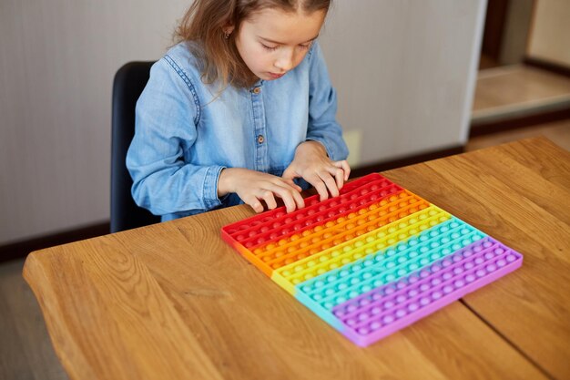 Bambina che gioca con un grande popit in silicone, una fossetta semplice, un giocattolo a bolle d'aria