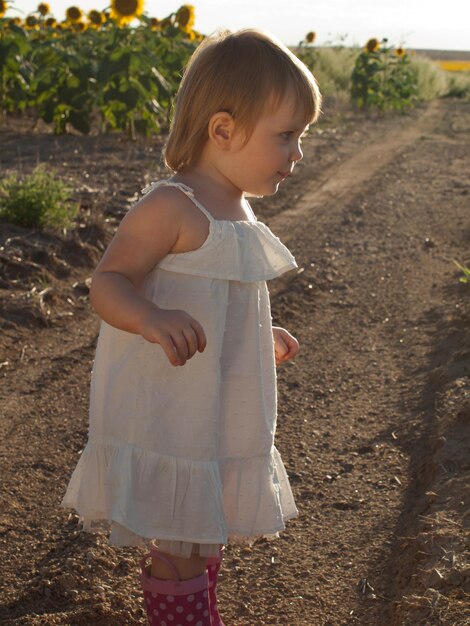 Bambina che gioca nel campo di girasoli.