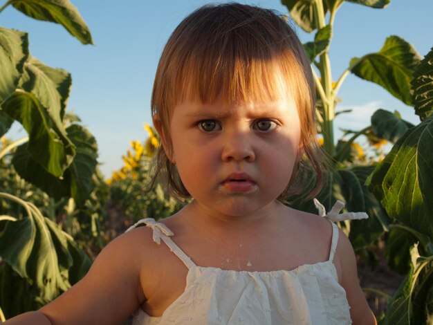 Bambina che gioca nel campo di girasoli.