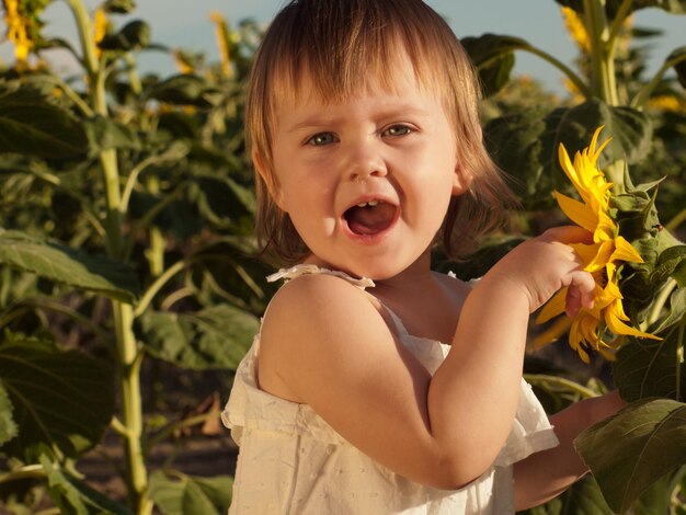 Bambina che gioca nel campo di girasoli.