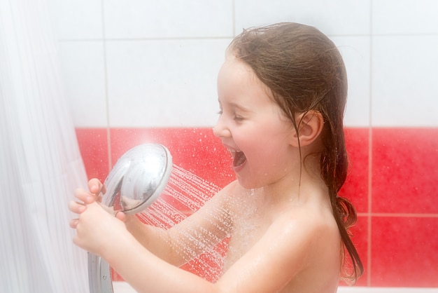 Bambina che gioca sotto la doccia, ridendo