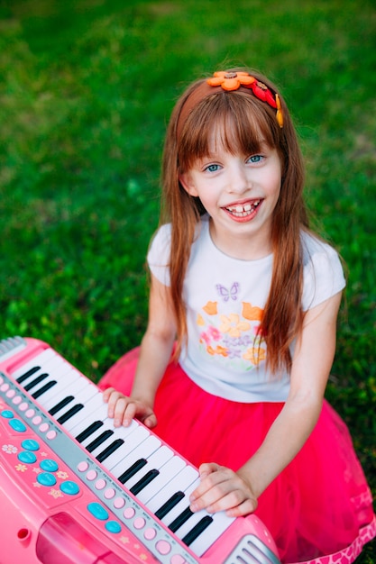 Bambina che gioca su un piano del giocattolo nel parco