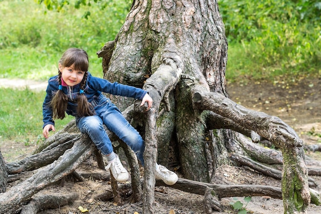 Bambina che gioca sulle radici di un albero