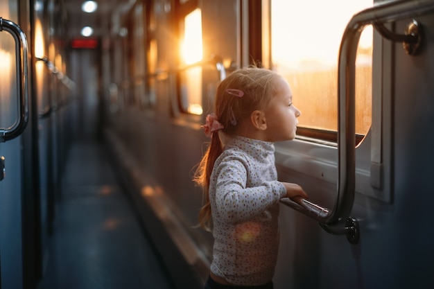 Bambina che guarda attraverso il finestrino del treno al tramonto