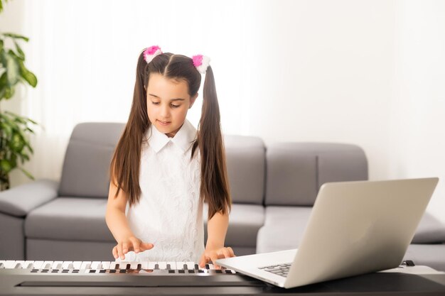 Bambina che guarda il tutorial della lezione online come imparare un sintetizzatore.