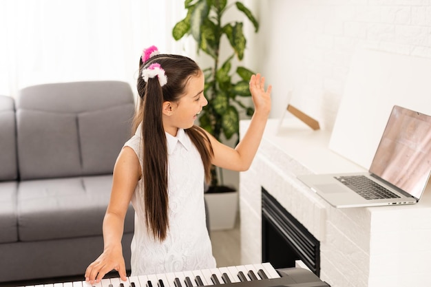 Bambina che guarda il tutorial della lezione online come imparare un sintetizzatore.