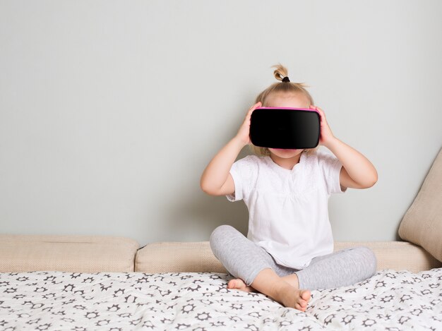 Bambina che guarda in occhiali per realtà virtuale a casa. Interni scandinavi