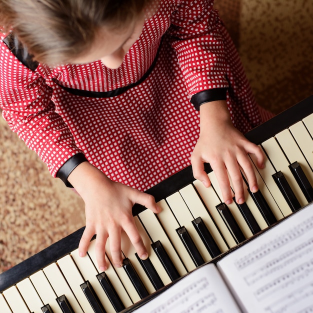 Bambina che impara a suonare il pianoforte a casa