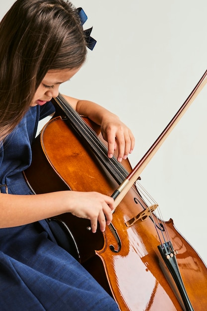 Bambina che impara a suonare il violoncello a casa