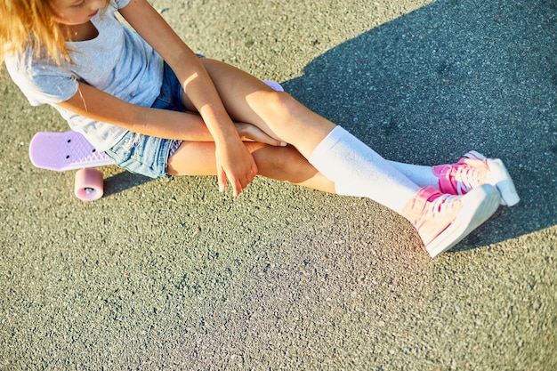 Bambina che impara a usare uno skateboard su una strada rurale della città estiva