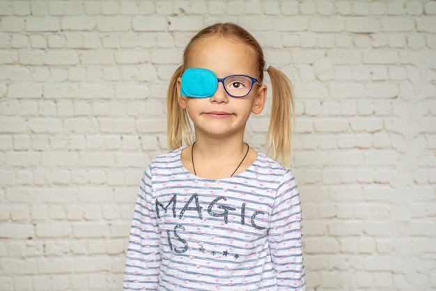 Bambina che indossa occlusore e occhiali da vista, trattamento dell'ambliopia e problemi di vista