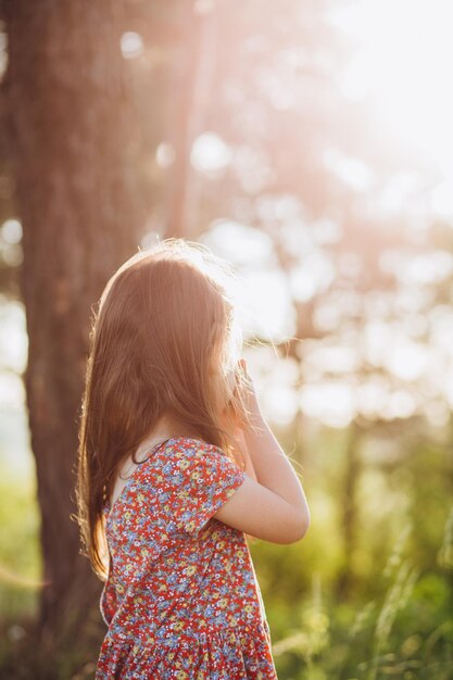 Bambina che indossa un abito rosa che fa una passeggiata tutta sola in un parco o in una foresta