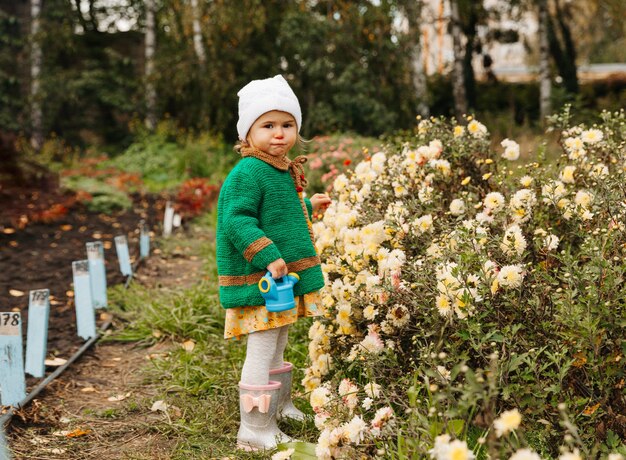 Bambina che innaffia i fiori con un annaffiatoio in giardino