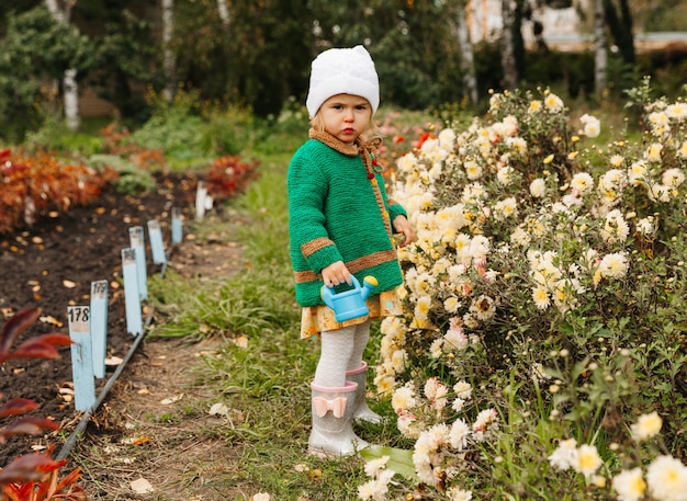 Bambina che innaffia i fiori con un annaffiatoio in giardino